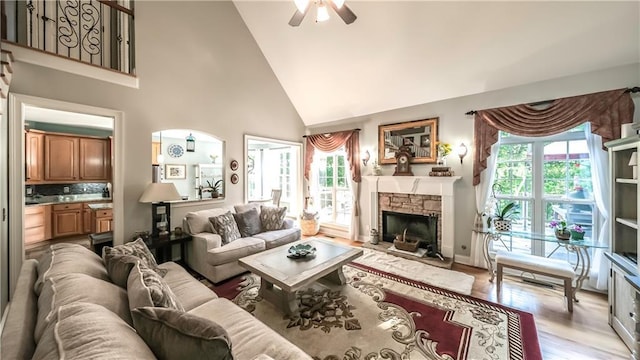 9742 Fallview Ct, Villa Rica, GA 30180 - living area with high vaulted ceiling, a ceiling fan, a stone fireplace, light wood finished floors, and baseboards