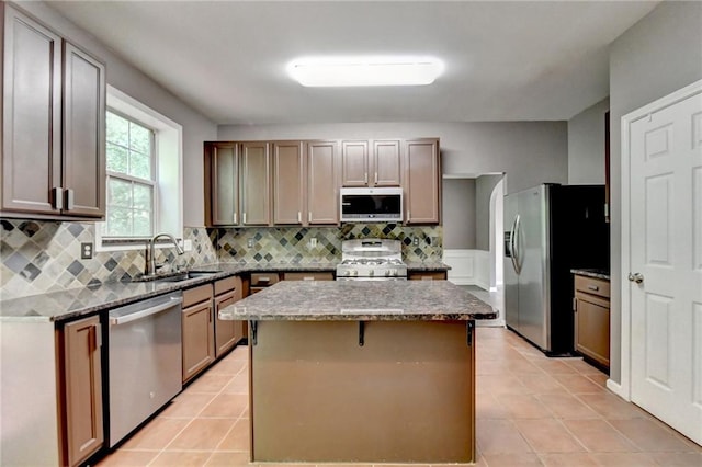 kitchen with appliances with stainless steel finishes, a center island, light tile patterned flooring, and sink