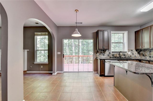 kitchen featuring sink, stainless steel dishwasher, backsplash, and light tile patterned floors