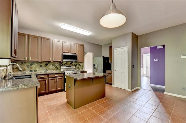 kitchen featuring a kitchen island, hanging light fixtures, sink, light tile patterned flooring, and stainless steel appliances