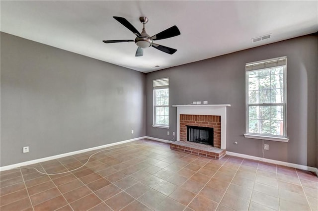 unfurnished living room featuring a fireplace, plenty of natural light, ceiling fan, and light tile patterned flooring