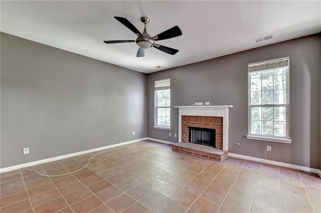 unfurnished living room featuring visible vents, a ceiling fan, a brick fireplace, baseboards, and tile patterned floors