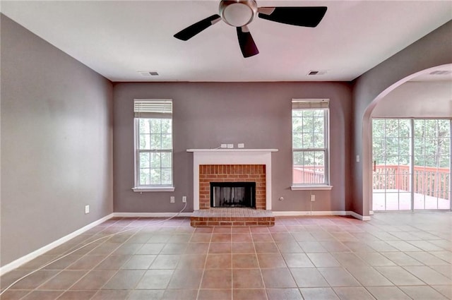 unfurnished living room with ceiling fan, a fireplace, and light tile patterned floors