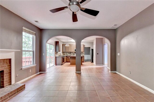 tiled living room featuring ceiling fan and a brick fireplace