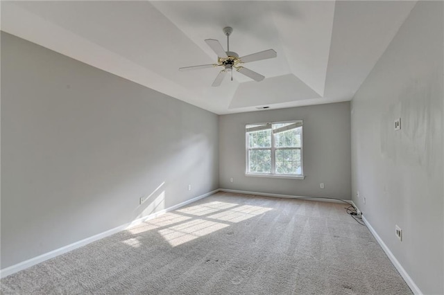 carpeted spare room featuring ceiling fan and a raised ceiling