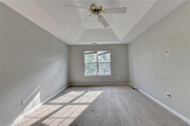 spare room featuring light colored carpet, a tray ceiling, and ceiling fan