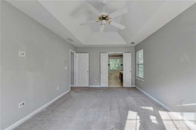 unfurnished bedroom featuring a tray ceiling, carpet flooring, visible vents, and baseboards