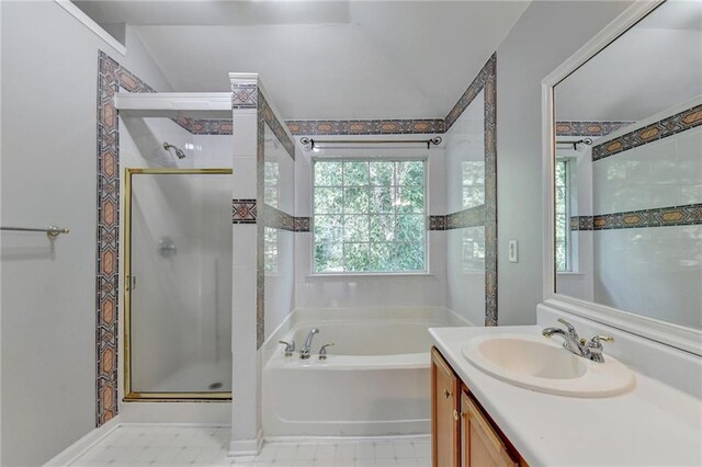 bathroom featuring tile patterned floors, vaulted ceiling, shower with separate bathtub, and vanity