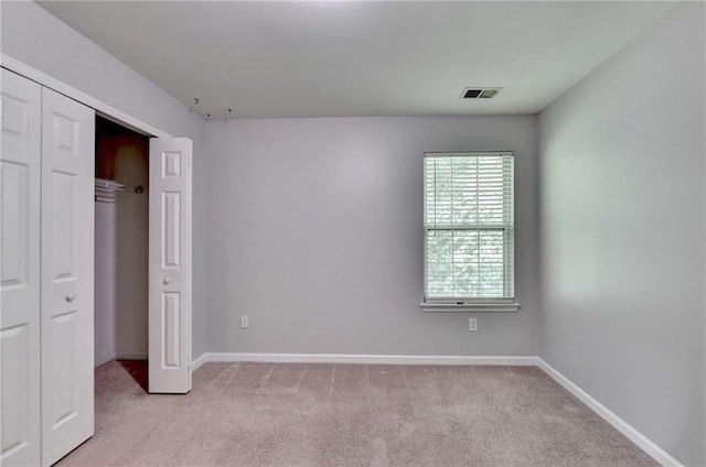 unfurnished bedroom featuring baseboards, visible vents, a closet, and light colored carpet