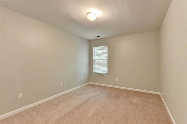 spare room featuring light carpet, visible vents, and baseboards