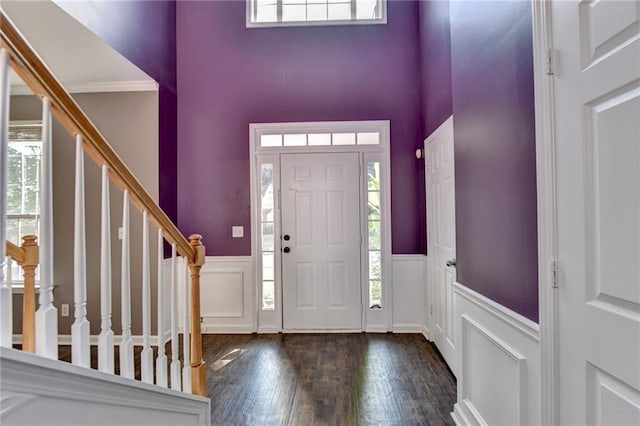 entrance foyer with a towering ceiling, crown molding, and dark hardwood / wood-style floors