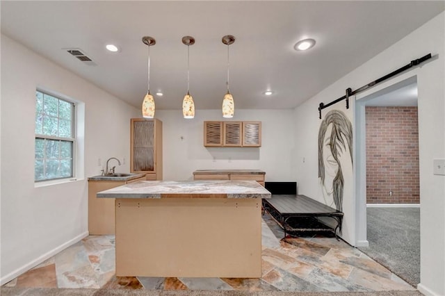 kitchen with a kitchen island, light colored carpet, hanging light fixtures, a barn door, and sink