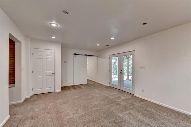 carpeted spare room with recessed lighting, a barn door, baseboards, and french doors