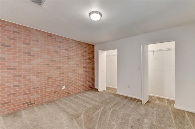 carpeted empty room with brick wall