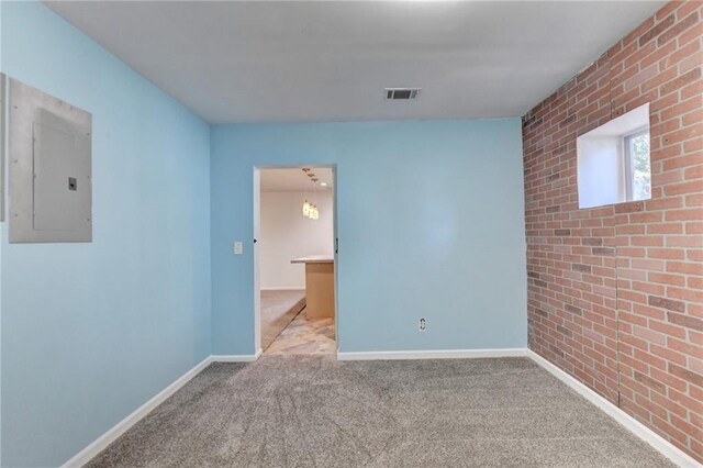 spare room featuring brick wall, light colored carpet, and electric panel