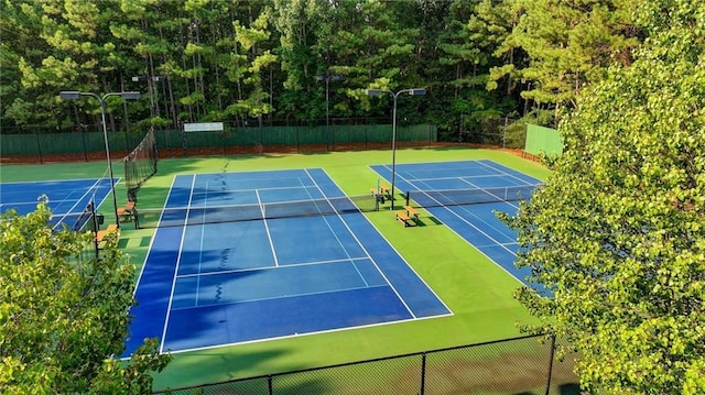 view of tennis court with community basketball court and fence