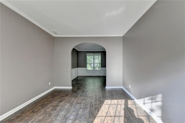 spare room featuring arched walkways, crown molding, baseboards, and wood finished floors