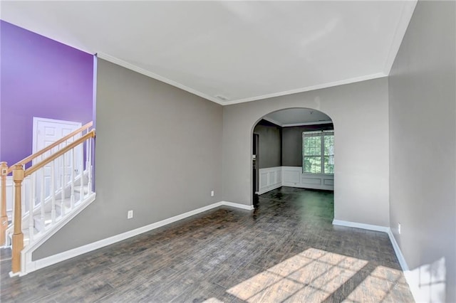 unfurnished room with arched walkways, wood finished floors, baseboards, stairs, and crown molding