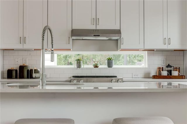 kitchen with white cabinets, decorative backsplash, and a breakfast bar