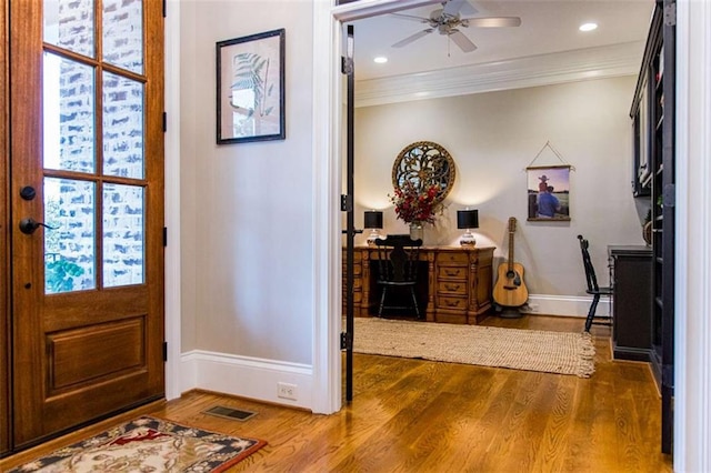 foyer entrance featuring baseboards, a ceiling fan, ornamental molding, and wood finished floors