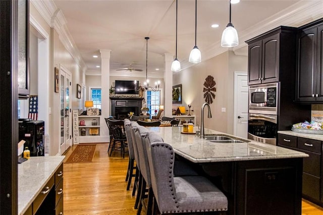 kitchen with stainless steel appliances, a sink, crown molding, open floor plan, and a kitchen breakfast bar