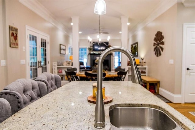 kitchen with a sink, open floor plan, ornamental molding, decorative light fixtures, and french doors