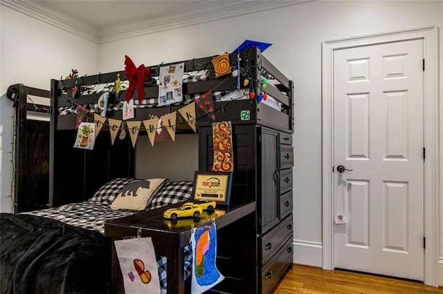 bedroom with wood finished floors and ornamental molding