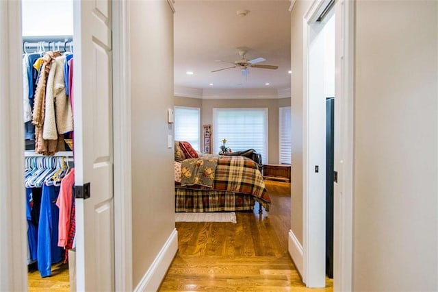 hallway with crown molding, wood finished floors, and baseboards