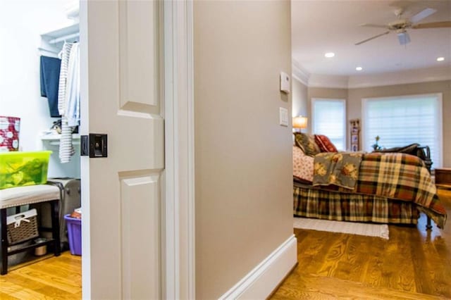 hall with wood finished floors, recessed lighting, and crown molding