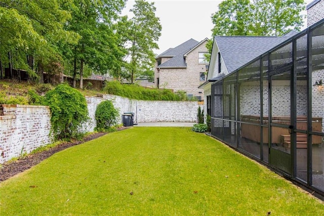 view of green lawn featuring glass enclosure