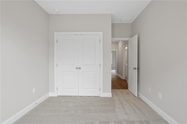 unfurnished bedroom with a closet and light colored carpet