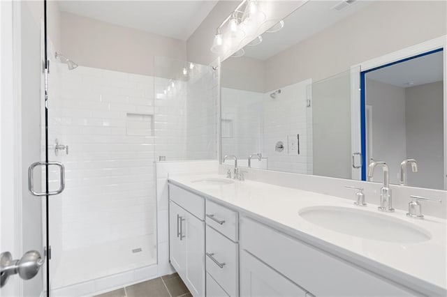 bathroom with a shower with shower door, double sink vanity, and tile patterned flooring