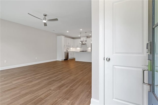 unfurnished living room featuring light hardwood / wood-style flooring, sink, and ceiling fan