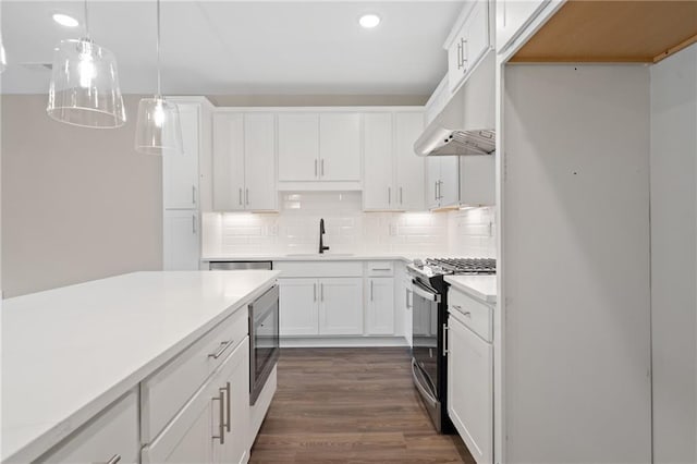 kitchen featuring hanging light fixtures, dark wood-type flooring, backsplash, stainless steel appliances, and sink