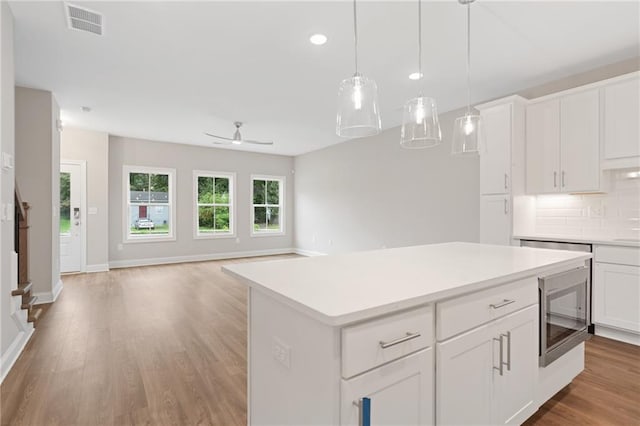 kitchen featuring white cabinets, light wood-type flooring, ceiling fan, and decorative backsplash