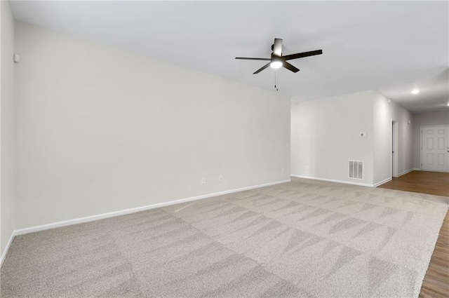 spare room with ceiling fan and light colored carpet