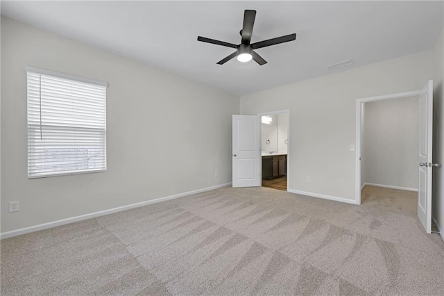 unfurnished bedroom featuring ensuite bath, light colored carpet, and ceiling fan