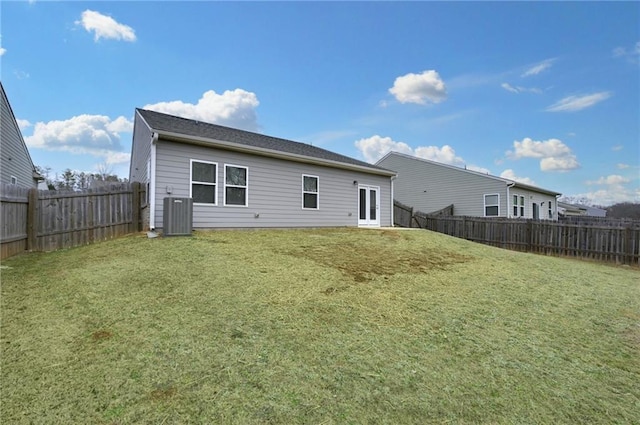 rear view of property with central AC unit and a yard