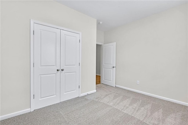 unfurnished bedroom with light colored carpet and a closet