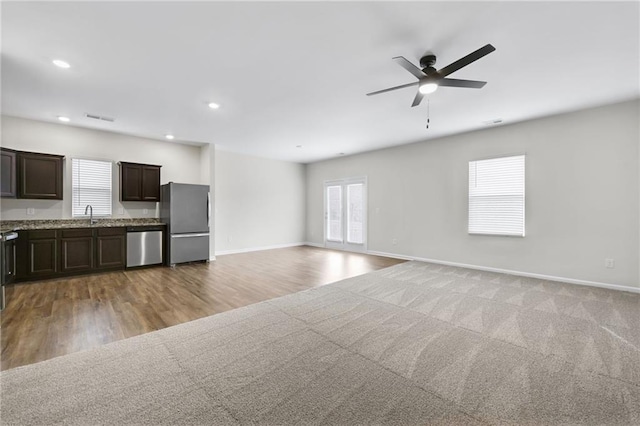 unfurnished living room with sink, ceiling fan, and light wood-type flooring