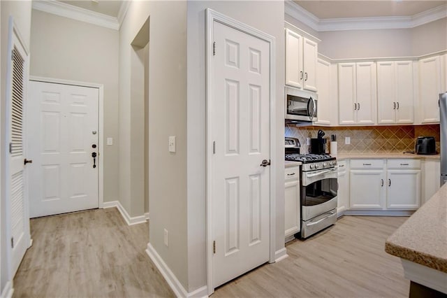 kitchen with stainless steel appliances, light wood-style flooring, white cabinets, and ornamental molding