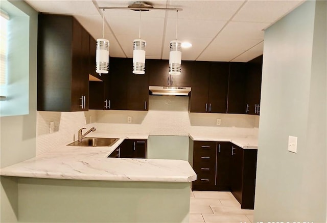 1202 Laurel Cliff Dr SE, Smyrna, GA 30082 - kitchen featuring a sink, under cabinet range hood, tasteful backsplash, a peninsula, and dark brown cabinets