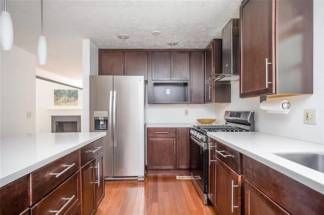 1202 Laurel Cliff Dr SE, Smyrna, GA 30082 - kitchen featuring stainless steel appliances, wall chimney range hood, light countertops, wood-type flooring, and hanging light fixtures