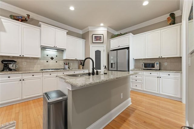 kitchen featuring stainless steel appliances, tasteful backsplash, white cabinetry, a sink, and recessed lighting