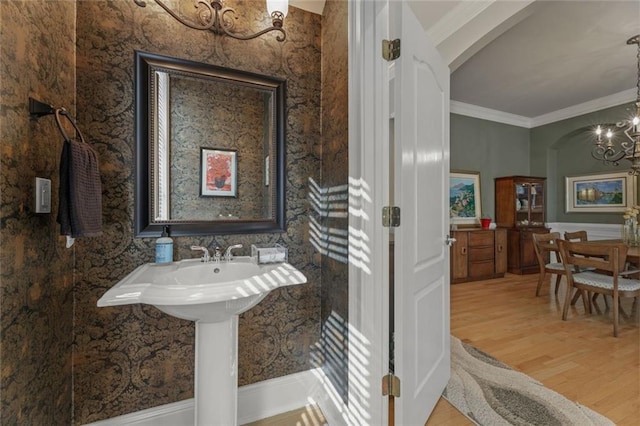 bathroom with a chandelier, wood finished floors, and ornamental molding