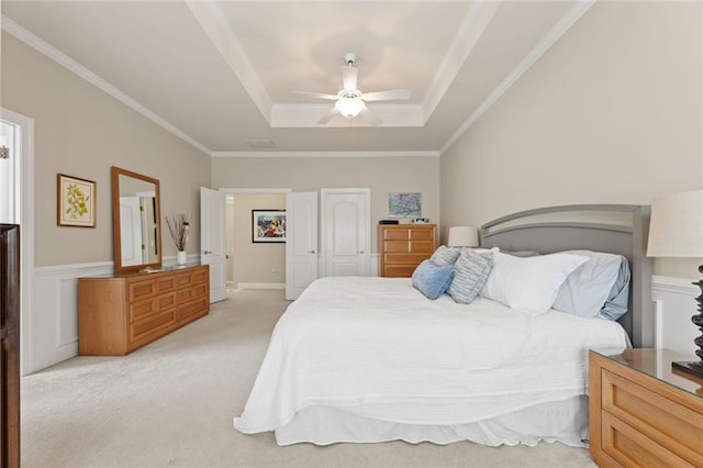 bedroom featuring a tray ceiling, light carpet, crown molding, and ceiling fan