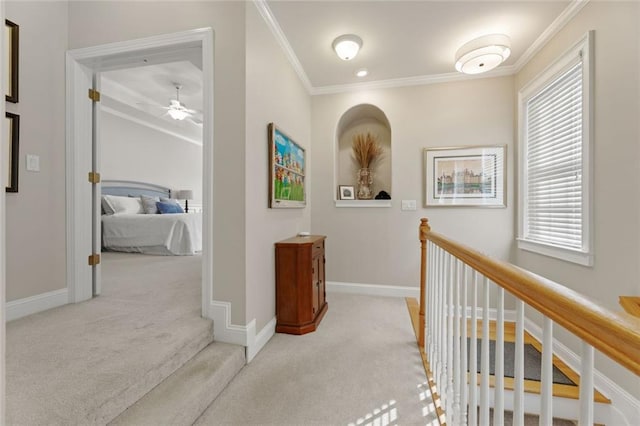 corridor with light colored carpet, ornamental molding, healthy amount of natural light, and baseboards