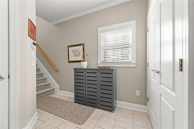 tiled foyer with stairs, baseboards, and crown molding