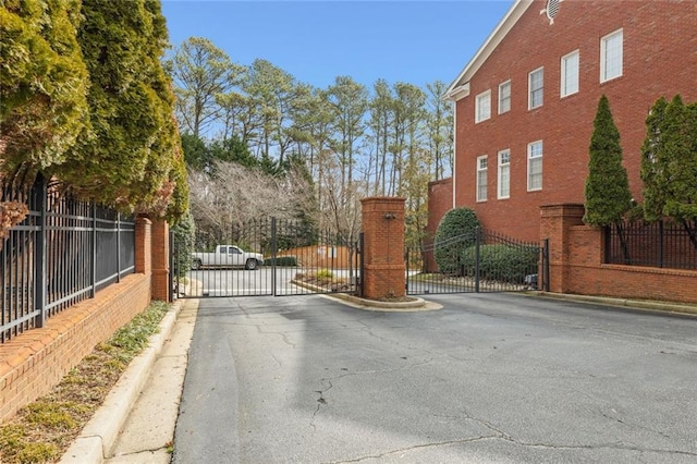 view of asphalt street featuring a gate, curbs, and a gated entry
