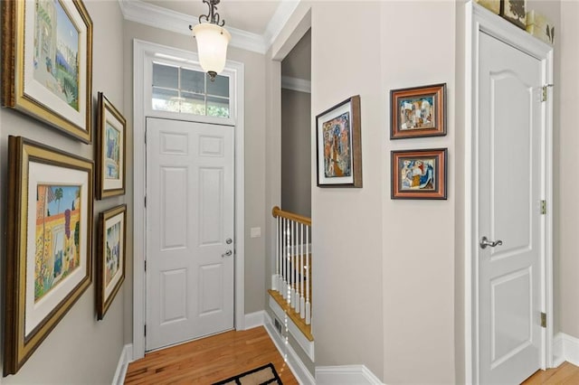 entryway with light wood-style flooring, baseboards, and crown molding